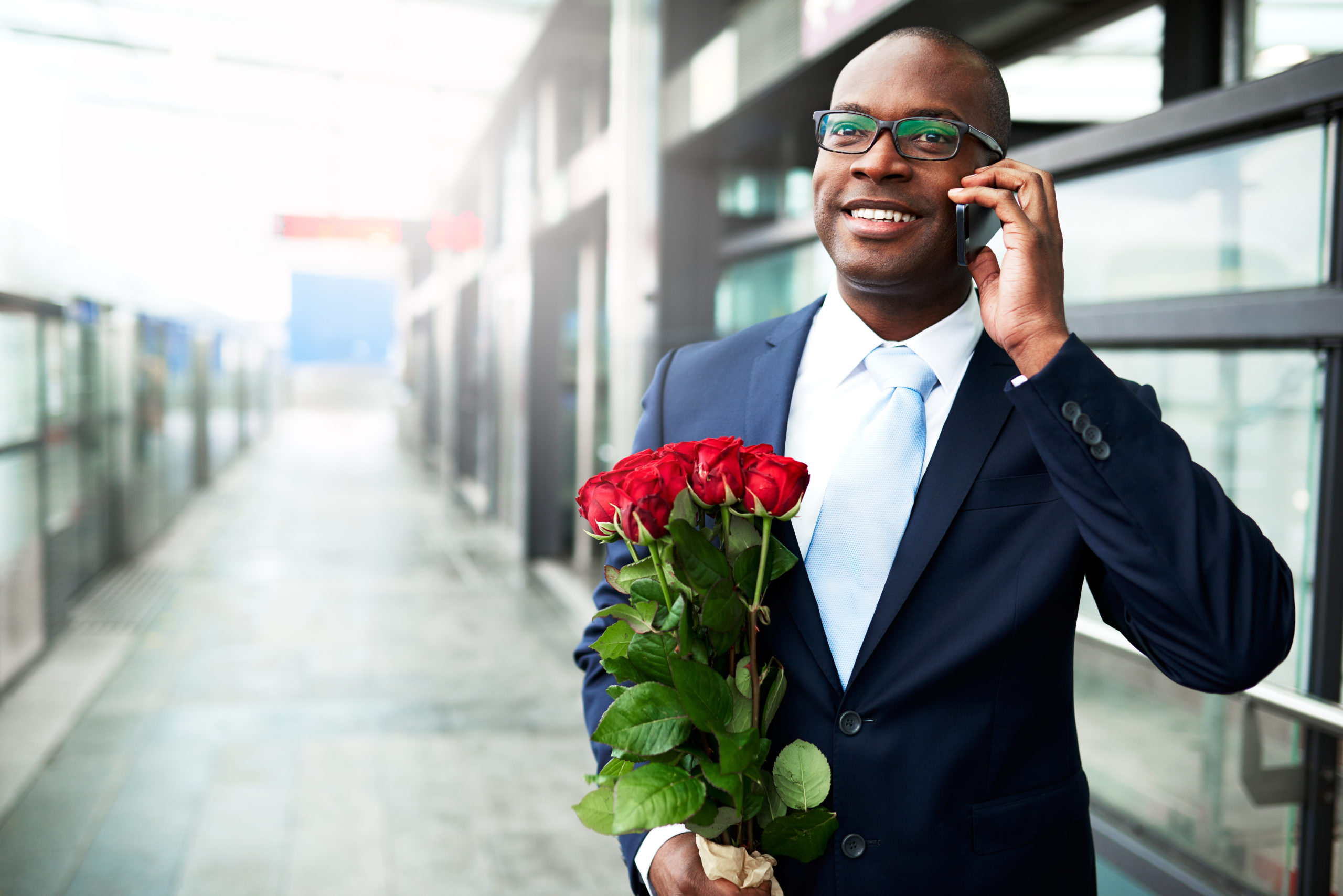 Happy Businessman with Flowers Calling on Phone